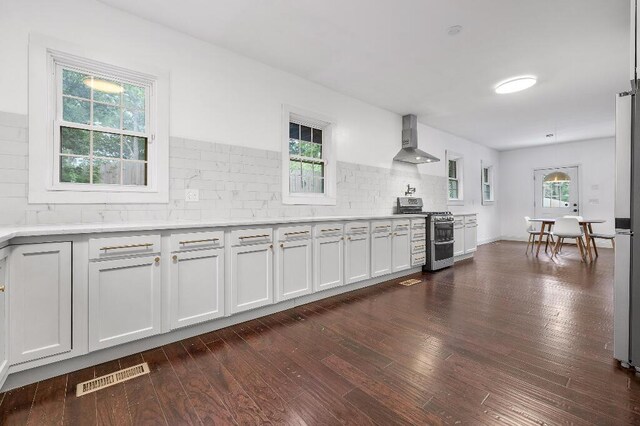 kitchen with white cabinetry, tasteful backsplash, stainless steel range oven, dark wood-type flooring, and wall chimney exhaust hood