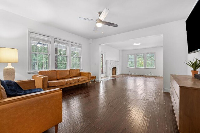 living room featuring dark wood finished floors, a fireplace, a ceiling fan, and baseboards