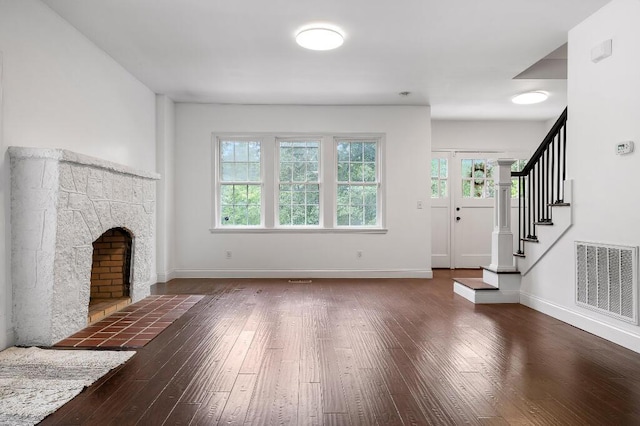 unfurnished living room with visible vents, baseboards, hardwood / wood-style floors, and stairway