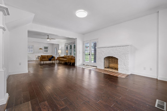 unfurnished living room featuring ceiling fan, dark hardwood / wood-style floors, and a stone fireplace