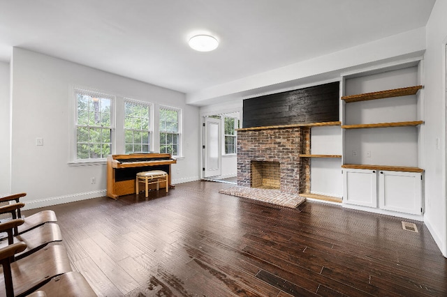 living room featuring dark wood-type flooring and a brick fireplace