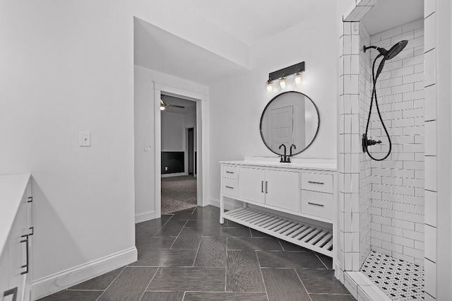 bathroom featuring tile patterned flooring, vanity, and a tile shower