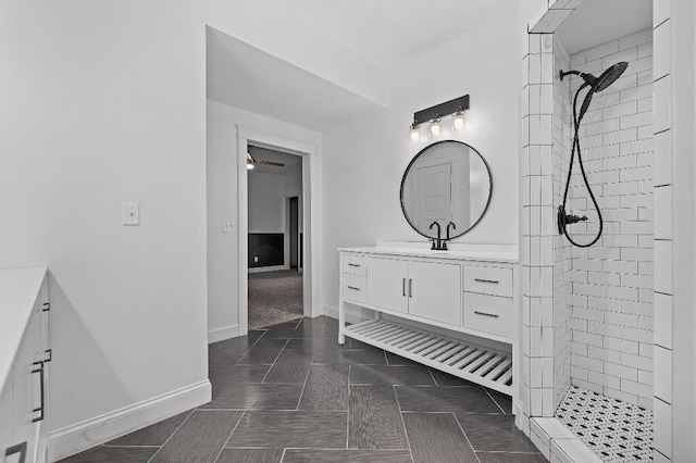 full bathroom featuring tile patterned floors, baseboards, vanity, and a tile shower