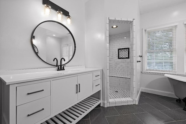 full bath with a tile shower, vanity, and baseboards