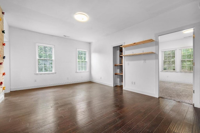 unfurnished living room with visible vents, baseboards, and dark wood-style flooring