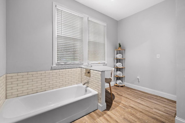 full bathroom featuring a garden tub, wood finished floors, and baseboards