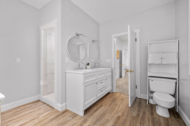 bathroom with walk in shower, vanity, toilet, and hardwood / wood-style floors