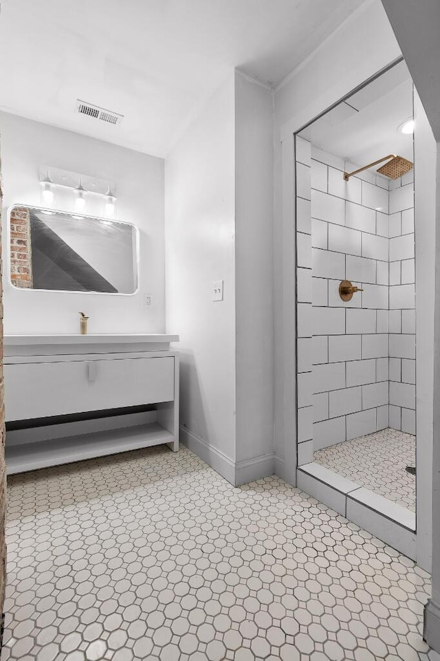 full bath featuring visible vents, tiled shower, baseboards, and vanity