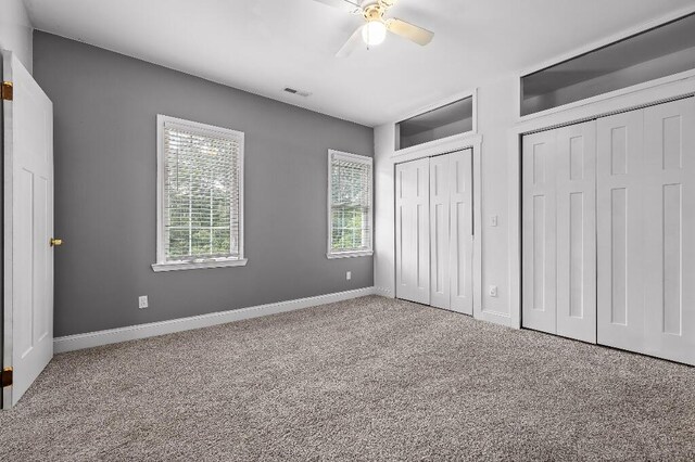 unfurnished bedroom featuring carpet flooring, two closets, and ceiling fan