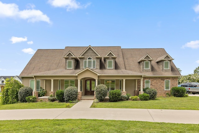 view of front facade with covered porch, a front lawn, and a shingled roof