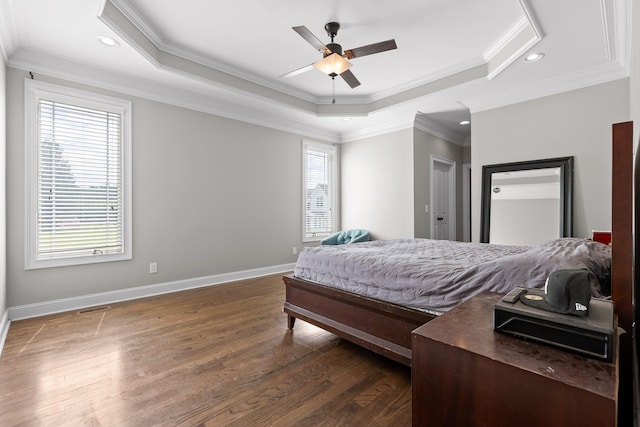 bedroom featuring a tray ceiling, baseboards, dark wood-type flooring, and ornamental molding