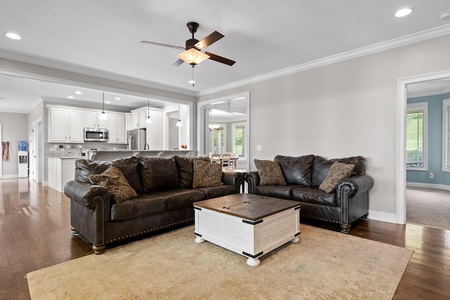 living room with ornamental molding, ceiling fan with notable chandelier, wood finished floors, recessed lighting, and baseboards