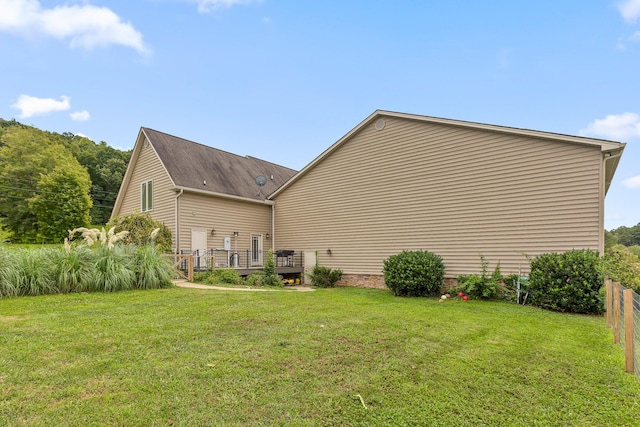 back of house featuring a wooden deck, a yard, and fence