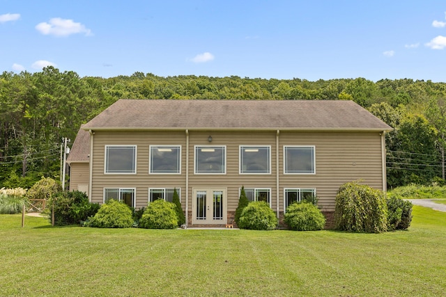 back of property featuring french doors, a view of trees, and a yard