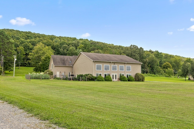 view of front facade with a wooded view and a front yard