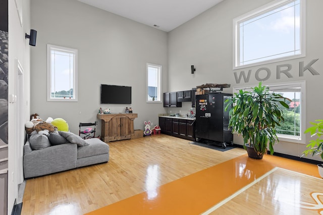 living room featuring visible vents, light wood-style flooring, and a towering ceiling