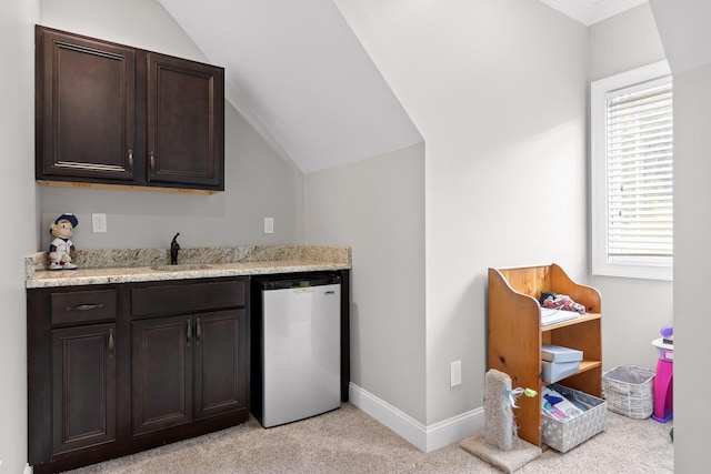 bar with baseboards, a sink, vaulted ceiling, light carpet, and dishwasher