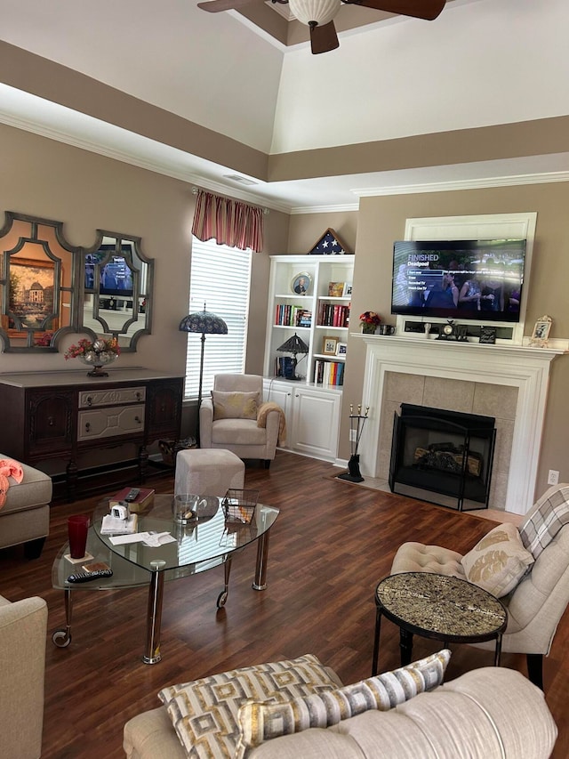 living room featuring a towering ceiling, wood-type flooring, ceiling fan, and a tile fireplace