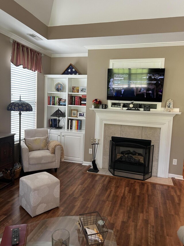 living room featuring ornamental molding, hardwood / wood-style flooring, and a tile fireplace