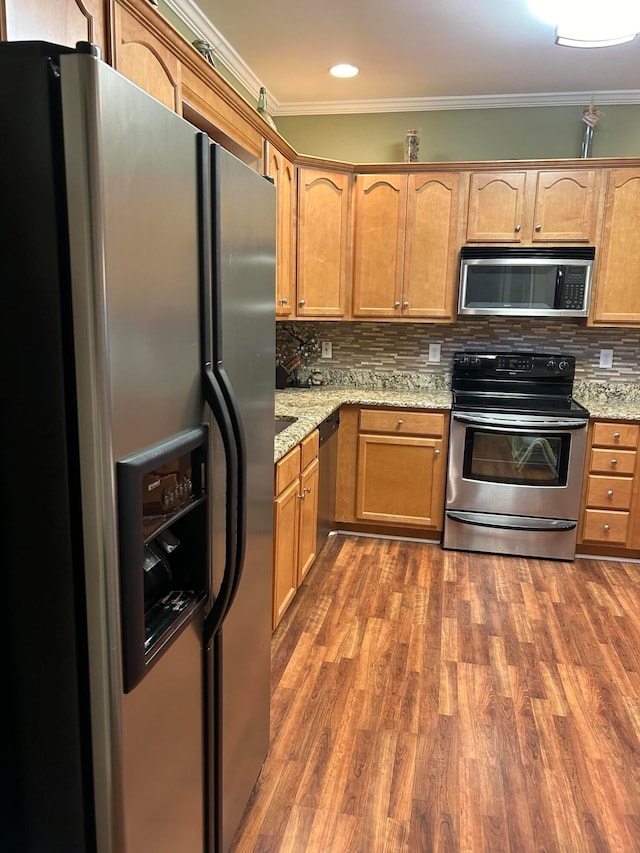 kitchen with dark wood-type flooring, stainless steel appliances, decorative backsplash, and ornamental molding