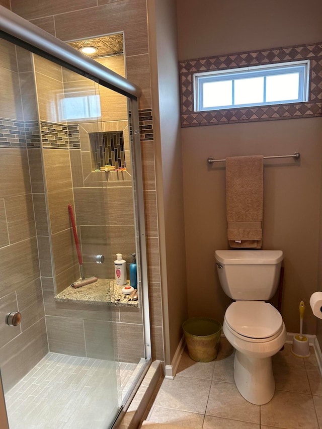 bathroom with a shower with door, toilet, and tile patterned flooring