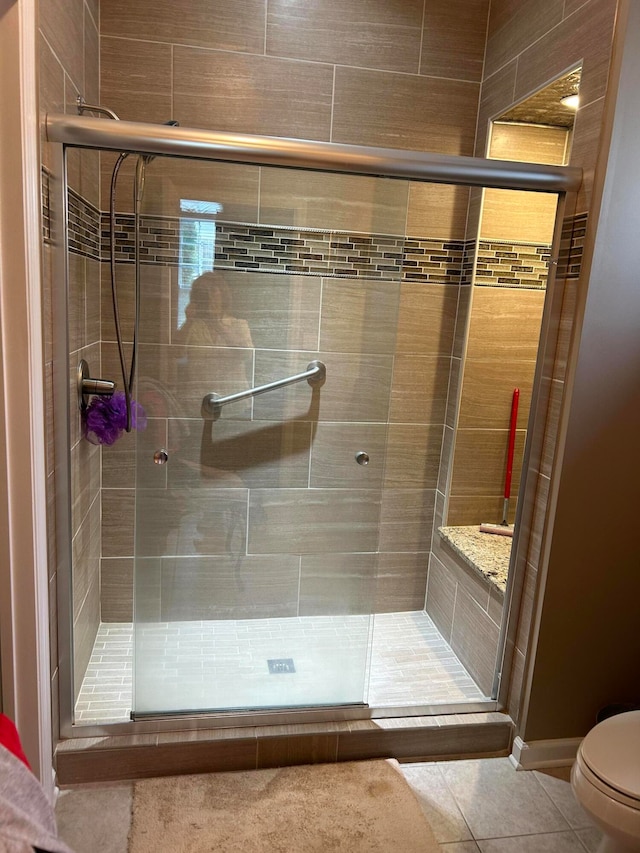 bathroom featuring toilet, an enclosed shower, and tile patterned flooring