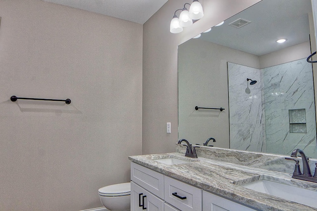 bathroom featuring vanity, toilet, and a tile shower