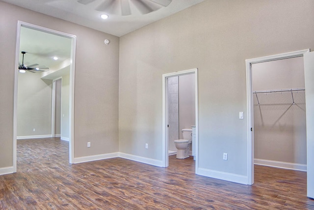 unfurnished bedroom featuring ceiling fan, dark hardwood / wood-style flooring, a spacious closet, and ensuite bath