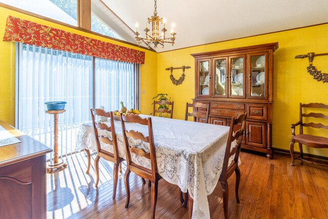 dining room with dark wood-type flooring, vaulted ceiling, and an inviting chandelier