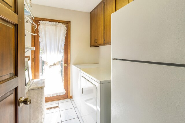 washroom featuring cabinets, washer and clothes dryer, and light tile patterned flooring