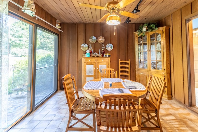 dining area with ceiling fan, wooden walls, wooden ceiling, and light tile patterned flooring