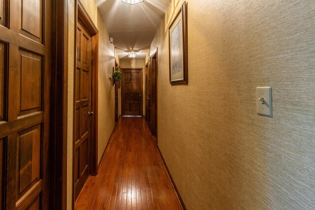 corridor featuring a textured ceiling and dark hardwood / wood-style flooring