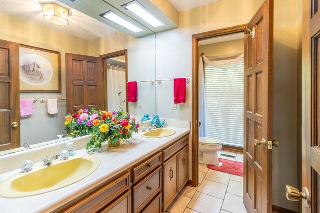 bathroom featuring tile patterned flooring, toilet, a textured ceiling, and vanity