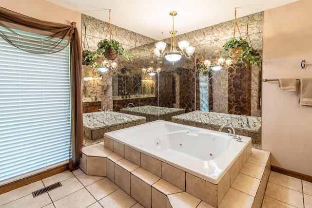 bathroom with a relaxing tiled tub, a notable chandelier, and tile patterned flooring