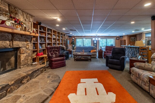 living room featuring a paneled ceiling, carpet flooring, and a stone fireplace