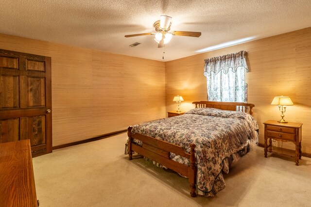 bedroom featuring light carpet, a textured ceiling, and ceiling fan