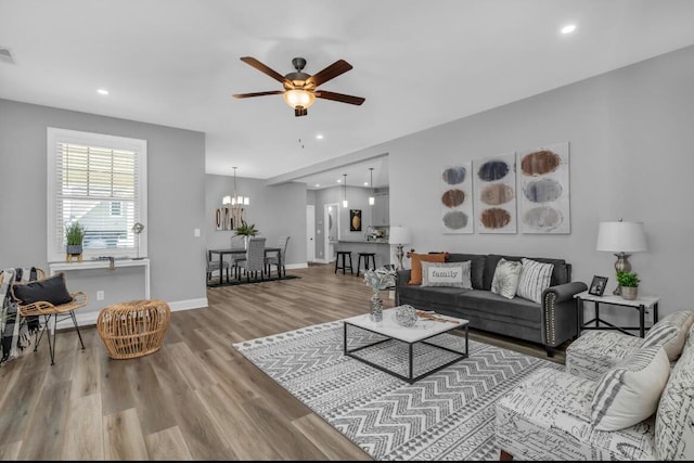 living room featuring light hardwood / wood-style flooring and ceiling fan with notable chandelier