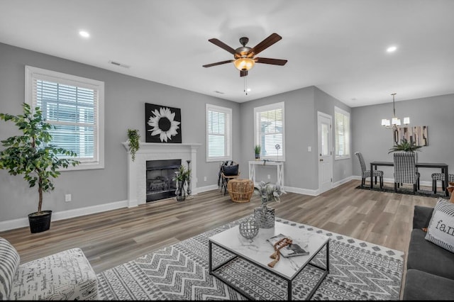 living room with ceiling fan with notable chandelier and hardwood / wood-style floors