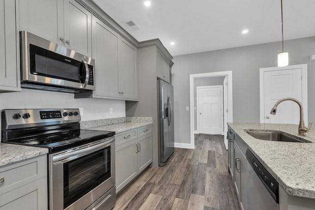 kitchen with appliances with stainless steel finishes, hardwood / wood-style flooring, gray cabinetry, and sink