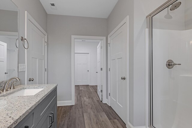 bathroom with hardwood / wood-style floors, walk in shower, and vanity