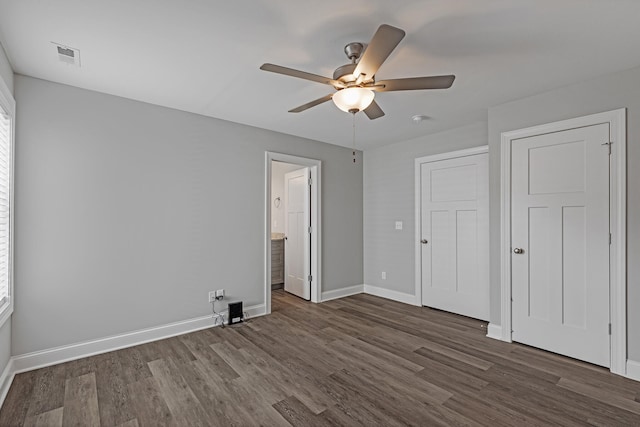 unfurnished bedroom with ceiling fan, dark hardwood / wood-style floors, and connected bathroom