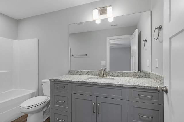 full bathroom with hardwood / wood-style floors, toilet,  shower combination, and vanity