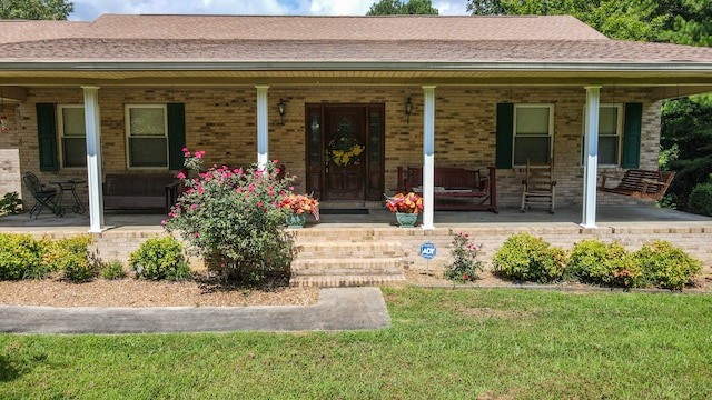 property entrance with a lawn and covered porch