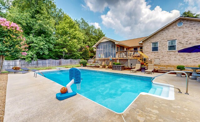 view of swimming pool with a sunroom, a diving board, a patio, and a deck