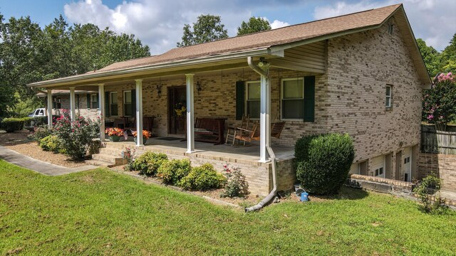 back of property featuring covered porch, a yard, and a garage