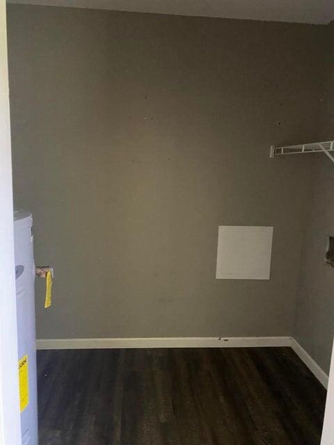 clothes washing area featuring dark hardwood / wood-style flooring and water heater