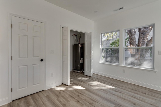 unfurnished bedroom with electric water heater and light wood-type flooring