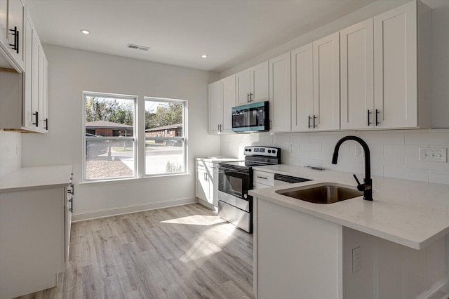 kitchen featuring white cabinets, sink, light hardwood / wood-style flooring, appliances with stainless steel finishes, and light stone counters