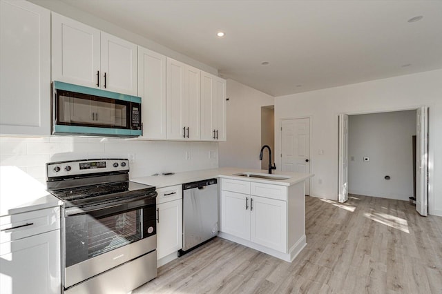 kitchen with sink, kitchen peninsula, light hardwood / wood-style flooring, white cabinetry, and stainless steel appliances