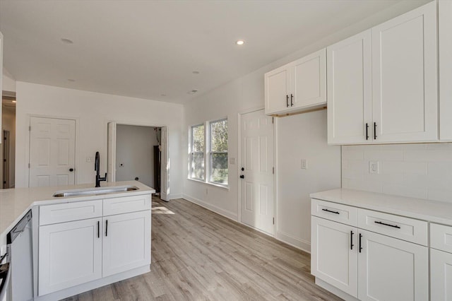 kitchen featuring dishwasher, sink, white cabinets, and light hardwood / wood-style floors